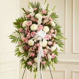 Tall standing spray of pink and white flowers with a white bow on an easel