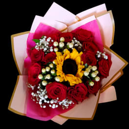 Bouquet of red roses with a sunflower center and pink wrapping