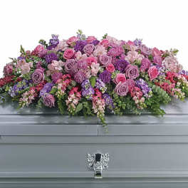 Large pink and purple floral casket spray on a gray casket