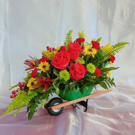 Bright mixed flower arrangement in a green wheelbarrow container