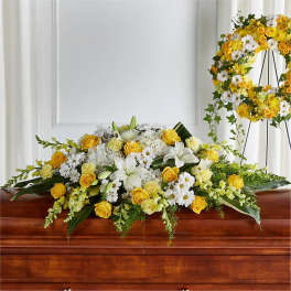 Yellow and white floral casket spray with a matching wreath on an easel