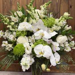 Tall white and green arrangement with orchids, roses, snapdragons and mums in a clear glass vase