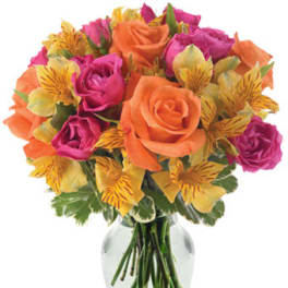 Bright bouquet of orange and pink roses with yellow alstroemeria in a clear glass vase