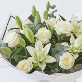 Bouquet of white lilies and roses wrapped in paper