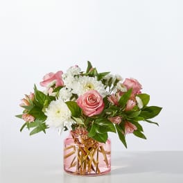 Pink roses and white daisies arranged in a pink glass vase.