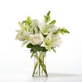White lilies and roses arranged in a clear glass vase