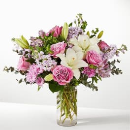 Pink roses and white lilies in a clear glass vase