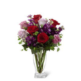 Tall clear vase with red and lavender roses mixed with purple flowers