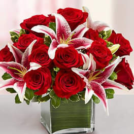 Arrangement of red roses and pink lilies in a square glass vase