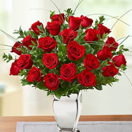 Tall arrangement of red roses in a clear glass vase on a table