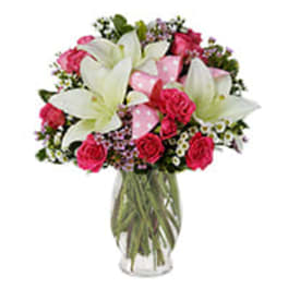 Vase arrangement of white lilies and bright pink roses with a polka dot ribbon.