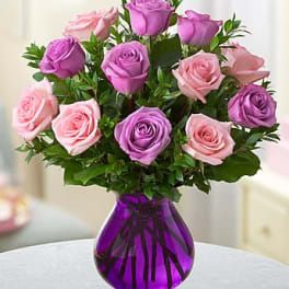 Arrangement of pink and lavender roses in a purple glass vase