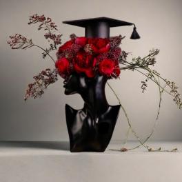 Red roses arranged on a black graduation cap and vase-shaped base