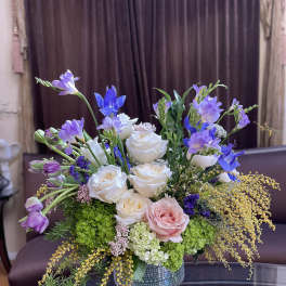 Mixed bouquet of white and pink roses with purple blooms in a glass vase