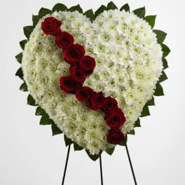 Heart-shaped white chrysanthemum wreath with red roses on a stand
