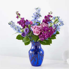 Pink and purple flowers arranged in a blue glass vase
