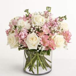 Pink and white roses arranged in a clear glass vase