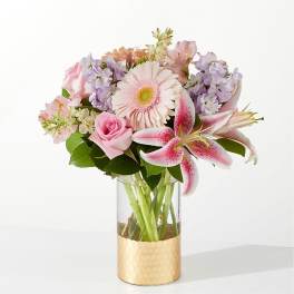 Pink and lavender bouquet in a clear vase with a gold base