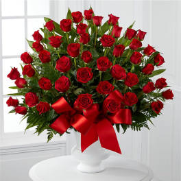 Large bouquet of red roses in a white vase with a red ribbon