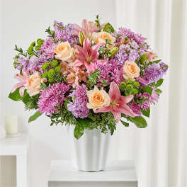 Pink lilies, roses, and purple mums in a white vase