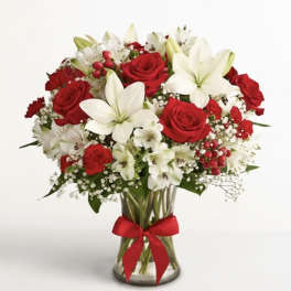Red roses and white lilies in a glass vase with a red ribbon