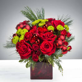 Red rose and green mum arrangement with pine and red ornaments in a red cube vase