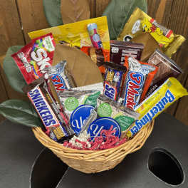 Basket of assorted candy bars with faux leaves behind it