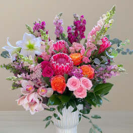 Pink and orange mixed flower arrangement in a white vase