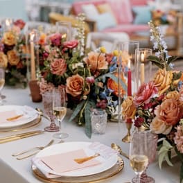 Floral table centerpieces with roses and candles on a set dining table