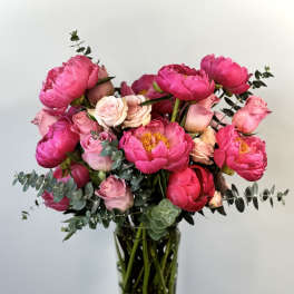 Pink peonies and roses arranged in a clear glass vase