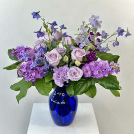Lavender and purple flowers arranged in a blue glass vase