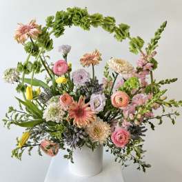 Mixed pastel bouquet in a white vase with pink, peach, and yellow blooms