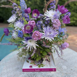 Mixed purple and pink bouquet in a vase on a book