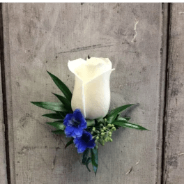 White rose boutonniere with blue flowers and greenery