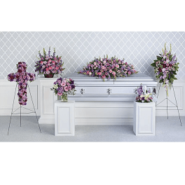 Pink and purple funeral flowers arranged around a silver casket