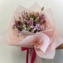 Hand-tied bouquet of mixed pink and purple dried flowers wrapped in layered blush paper with a hot pink ribbon.