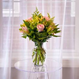 Pink roses and yellow lilies in a clear glass vase