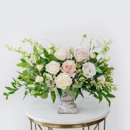 Blush and white roses arranged in a gray pedestal vase
