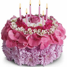 Pink floral cake with lit candles on top