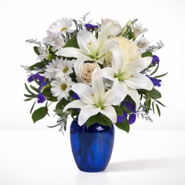 White lilies and daisies in a blue glass vase
