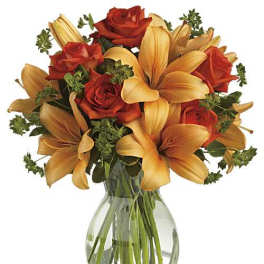 Arrangement of orange lilies and red-orange roses in a clear glass vase