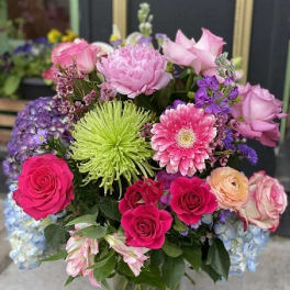 Mixed bouquet of pink, purple, and green flowers in a glass vase
