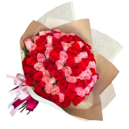 Bouquet of red and pink roses wrapped in brown paper with ribbon