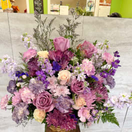 Large mixed bouquet of pink, purple, and cream flowers in a basket