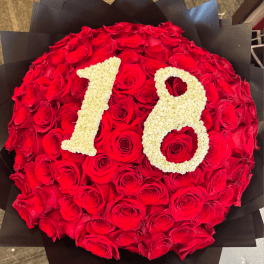 Round bouquet of red roses with cream-colored numbers 78 on top