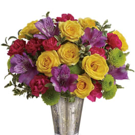 Mixed arrangement of yellow roses, purple alstroemeria, pink carnations, and green mums in a silver glass vase