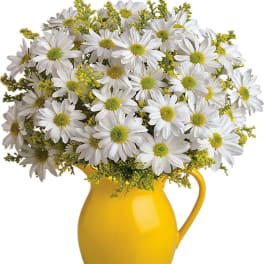 White daisy bouquet with yellow fillers arranged in a bright yellow ceramic pitcher