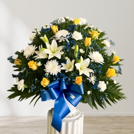 Large bouquet of white lilies, yellow roses, and white chrysanthemums with a blue ribbon