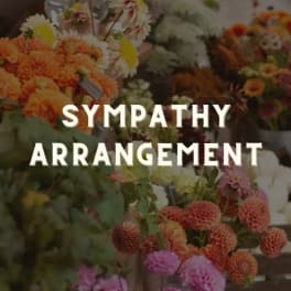 Sympathy arrangement with orange and pink flowers