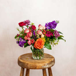 Mixed bouquet of roses and purple flowers in a glass vase